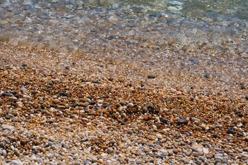 Closeup shot of the coastline with clear water and pebbles