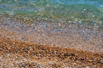 Closeup shot of the coastline with clear water and pebbles