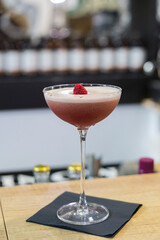 A beautiful cocktail garnished with raspberries.