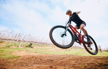 Bicycle jump, countryside and woman on a bike with speed for sports on a dirt road. Fitness, exercise and fast athlete doing sport training in nature on a park trail for cardio and cycling workout