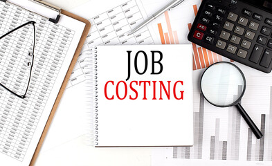 JOB COSTING text on notebook with clipboard and calculator on a chart background