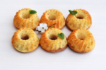 Mini bundt cakes decorated with lemon balm leaves and spring blooming twig, light background