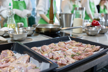 Quail carcasses lie on a baking sheet. Small birds are prepared for cooking
