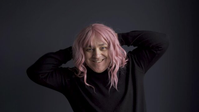 Portrait of a man in a pink wig, looking at the camera, grimacing, posing. close-up.
