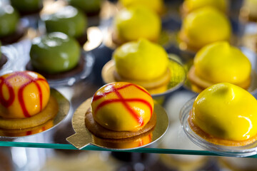 Yellow and green glazed cakes on showcase.