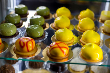 Yellow and green glazed cakes on showcase.