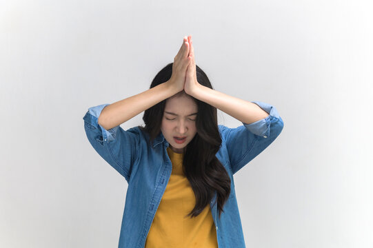 Portrait photo of funny Asian woman in colorful clothing posing begging, asking or making a wish on white background. People overacting posing gesture funny concept.