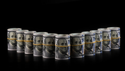 Rolled up american dollars standing in a line on a black background