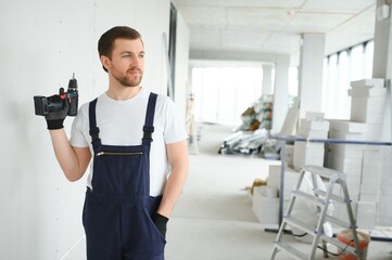 Fototapeta premium man drywall worker installing plasterboard sheet to wall.