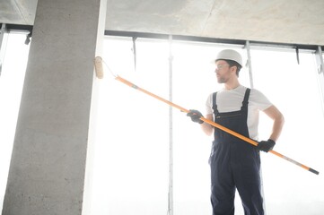 Painter man painting the wall, with paint roller.