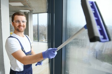 An employee of a professional cleaning service washes the glass of the windows of the building....