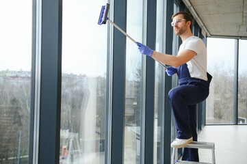 An employee of a professional cleaning service washes the glass of the windows of the building....