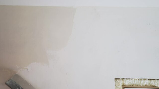 Construction worker align the old bathroom wall with trowel and plaster. A professional finisher painter levels the walls with putty with a wide spatula - wall decoration for wallpaper and painting. 