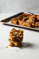 Stack of squares of Blondie cookies with pecan nuts on white marble countertop. White chocolate sweet and tasty, chewy cookie bars. 