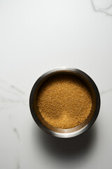 Brown sugar in metal bowl on white marble kitchen countertop background. Top view. Copy space