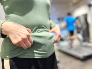 フィットネスジムでお腹をつまむ女性