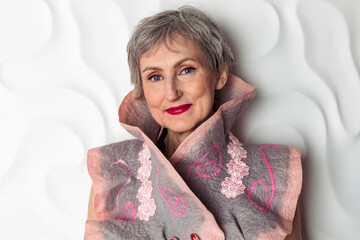 A fashionable elderly lady in a blue and white dress and a stylish collar is posing against a white background.