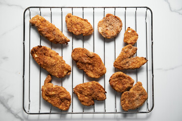 Close Up of Baked Chicken Schnitzel in breadcrumbs schnitzel on grid. 