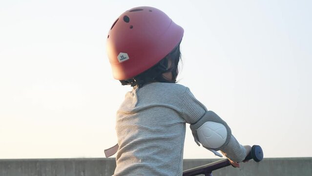 Closeup little cute cheerful asian preschooler kid on biking with safety helmet. Child having fun outdoor activity. Playful toddler playing in natural park. Growth development, childhood memories