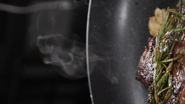 Steam or Vapour clouds rising from frying pan on stove. Vertical footage. Steam from pan while cooking. Cooking process in slow motion. Steam and white smoke rising on dark background. Full hd