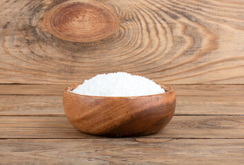 Wooden bowl with coconut flakes on a wooden background.