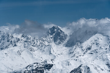 Alpine landscape with peaks covered with snow and clouds