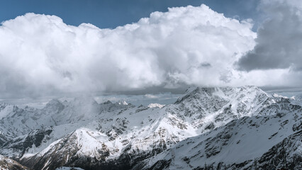 Fototapeta na wymiar Alpine landscape with peaks covered with snow and clouds