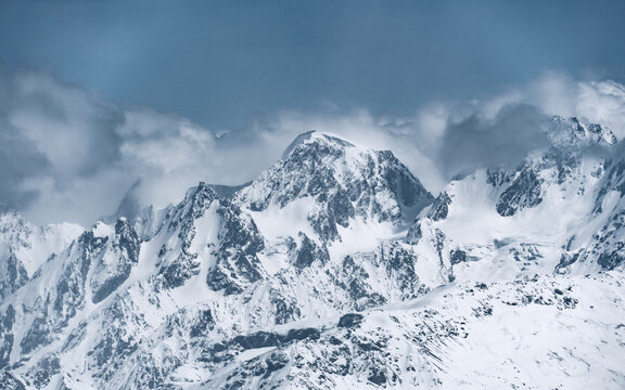 Alpine landscape with peaks covered with snow and clouds