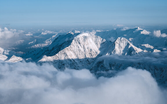 Snowy mountains in the clouds. Beautiful landscape with snowy rocks
