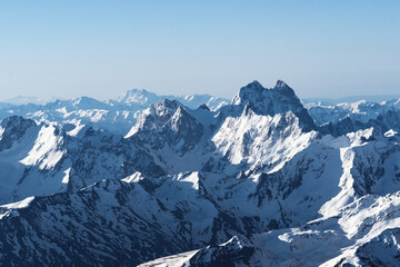 View of Mount Ushba and snow-covered peaks on a cloudy day from the top of Mount Elbrus