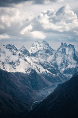 View of the valley and Mount Ushba and snow-covered peaks on a cloudy day