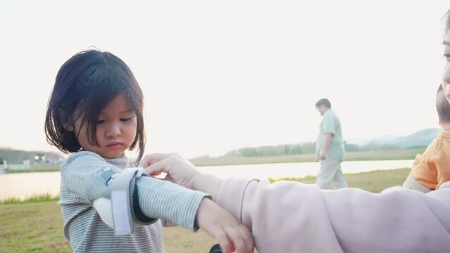 Asian girl remove elbow safety gear after done playing outside with mother helping hands, family relationship, child support and encourage, parents taking care of their kids, children innocence habit