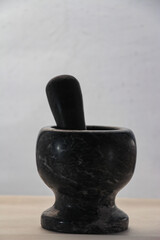 This photo shows a black marble mortar and pestle, commonly used in cooking to grind herbs and spices.The natural variations in the marble create an interesting pattern and texture.