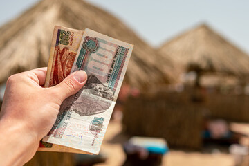 Egyptian pounds in a man's hand on the background of the beach. Egyptian money