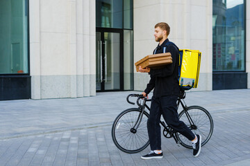 The courier is in a hurry to give the order to the customer. A pizza delivery man walks down the street