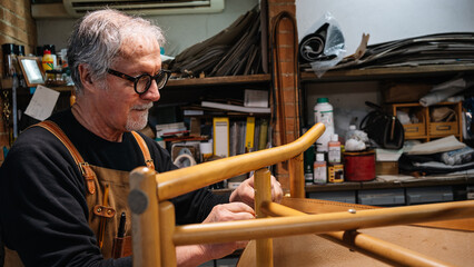tanner gluing the leather parts to a chair made by hand in a small shop in rome center. traditional...