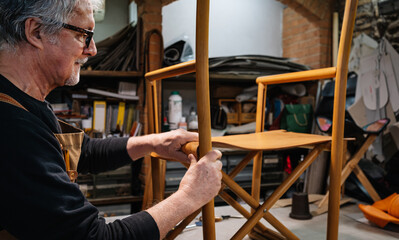 tanner placing the leather parts to a leather chair made by hand in a small shop in rome center....