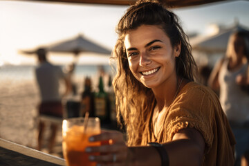 Generative AI illustration of cheerful female barista in casual shirt smiling and looking at camera with glass of cold cocktail on sandy beach near bar counter
