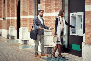 Man and woman standing in front of cash machine