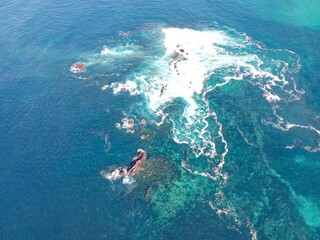 Fototapeta na wymiar aerial view of waves crashing on some rocks