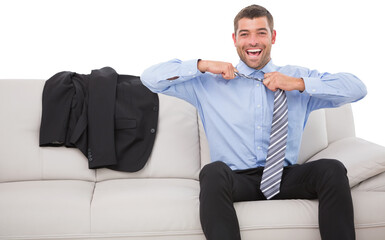 Cheerful businessman loosening his tie on sofa