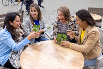 May 21, 2021, Antwerp, Belgium, Four attractive young woman of mixed race toasting with a cocktail...