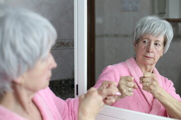 Senior woman ready to fight her mirror reflection 