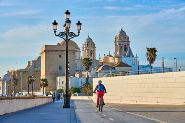 nice, active senior woman cycling with her electric mountain bike at the waterfront of old moorish city of Cadiz, Andalusia, Spain © Uwe