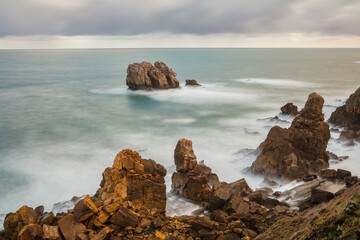 Long exposure image of the rocky coast of Cantabria in overcast weather, Spain