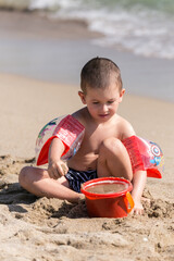 little happy boy play with sand and toys on summer beach