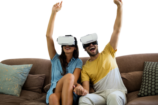 Cheerful couple wearing virtual reality glasses while sitting togerher on sofa