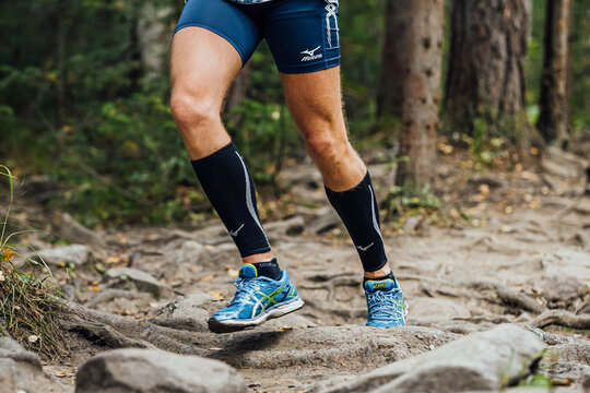 male runner run forest trail marathon in Mizuno compression sleeves, tights and Asics running shoes