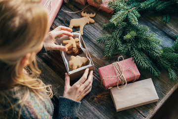 A woman wraps New Year's gifts with gingerbread cookies.