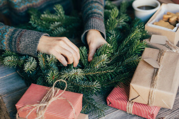 A woman makes a spruce Christmas wreath and wraps gifts.